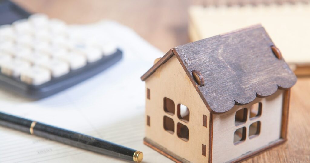 Wooden house model next to a calculator and pen, representing a first-time buyer working out their Ontario down payment