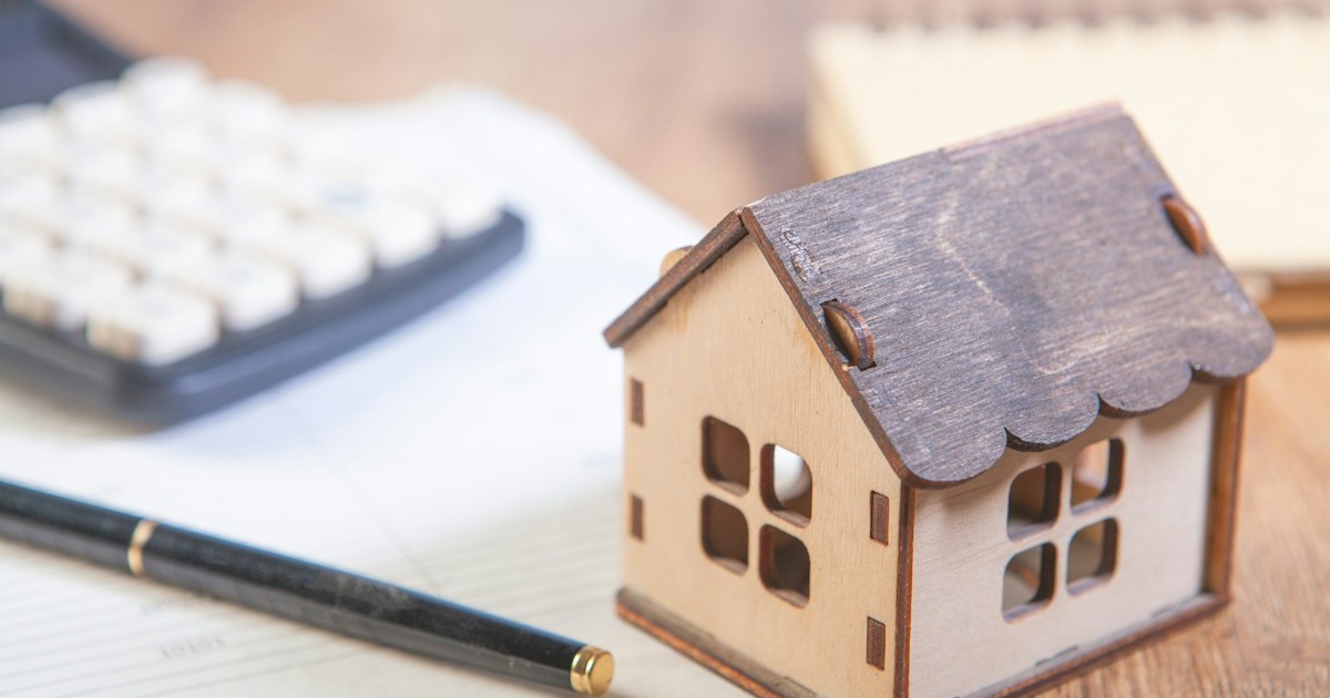 Wooden house model next to a calculator and pen, representing a first-time buyer working out their Ontario down payment